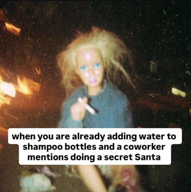 A meme featuring a doll with messy blonde hair, blue eyes, and a blue sweater, holding a cigarette. The background is dark and chaotic with blurred lights, creating a tense atmosphere. Overlaid text reads: 'when you are already adding water to shampoo bottles and a coworker mentions doing a secret Santa,' humorously capturing the stress of financial strain combined with the unexpected obligation of workplace gift exchanges.