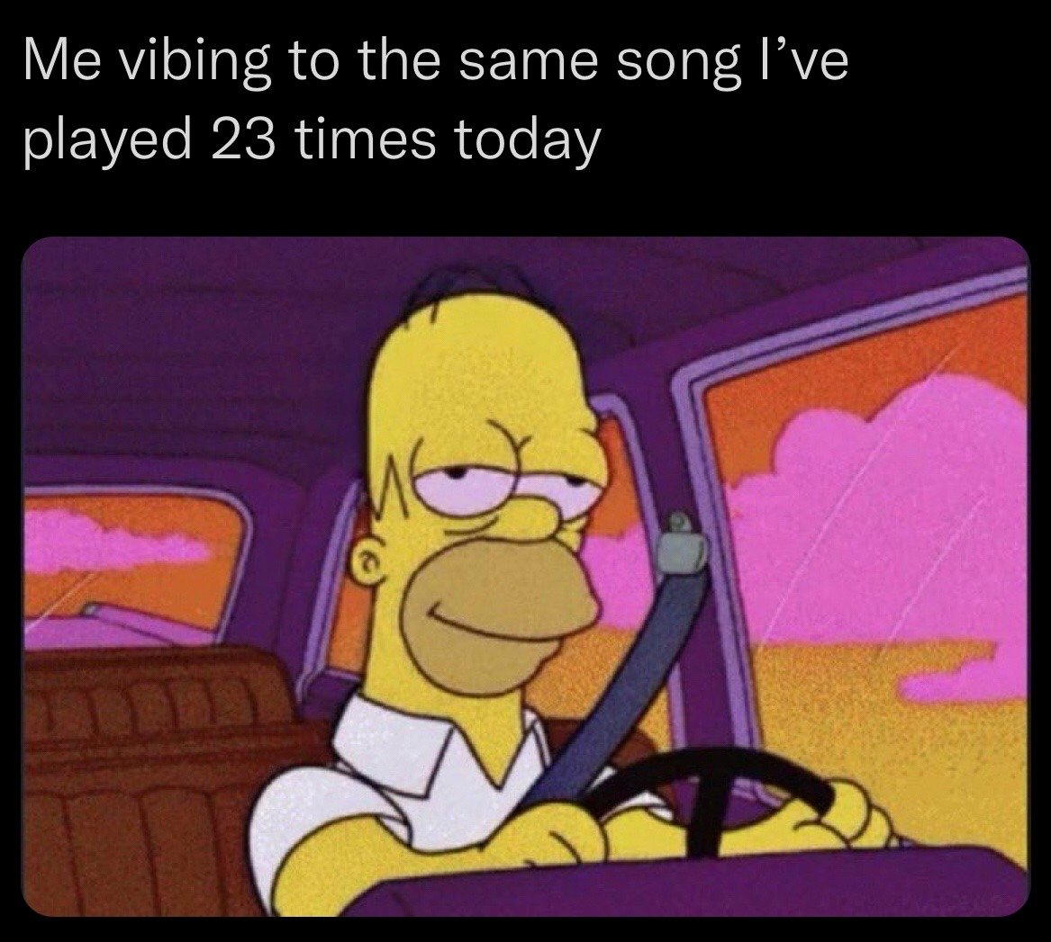 The meme has a black top bar with white text, followed by a still frame from the animated series *The Simpsons*. The top text reads 'Me vibing to the same song I’ve played 23 times today'. The image below shows Homer Simpson sitting in the driver's seat of a car, wearing his signature white collared shirt and a seatbelt, holding the steering wheel with both hands. He has a relaxed, half-lidded, smugly content expression that perfectly captures the feeling of happily enjoying a favorite song one has replayed excessively. The background visible through the car windows shows a warm sunset sky with pink clouds against an orange backdrop.