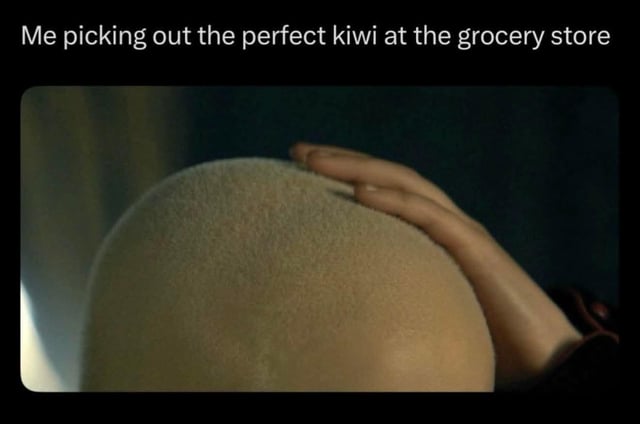 This meme uses a visual pun to create humor. The top text reads *"Me picking out the perfect kiwi at the grocery store"*, while the image below shows a close-up shot of a hand resting on a shaved human head. The joke relies on the nearly identical fuzzy texture and rounded shape of a bald head matching that of a kiwi fruit, exaggerating the relatable, careful process of selecting ripe produce by replacing the actual fruit with an unexpected human stand-in. It plays on the double meaning of the visual: what looks like a kiwi at first glance is revealed to be a person's head, pairing a mundane everyday task with an absurd visual gag.