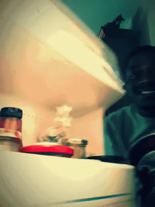 The GIF depicts a Black man in a dimly lit, teal-hued room reacting to content he is viewing. He first appears expectant and slightly amused with his tongue poking out, then his expression fades to neutral disappointment, he glances away unimpressed, and finally turns his back fully to leave the area. This visual conveys the relatable feeling of letdown when a user visits the r/memes subreddit hoping to view lighthearted funny content, only to be confronted with unwanted low-quality political posts instead.