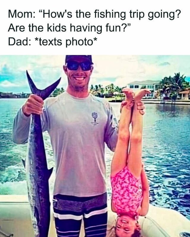 This meme combines text dialogue at the top with a candid photograph. The text sets up a conversation: Mom asks Dad how the family fishing trip is going, and if the kids are having fun. Dad responds by sending the accompanying photo: a smiling dad stands on a fishing boat out on the water, holding a large caught marlin in one hand, and holding his young daughter upside down by her ankles with his other hand. The daughter is laughing and clearly enjoying the playful moment. The meme jokes about the stereotypical laid-back, playful style of dad parenting, where dads prioritize fun over overly cautious supervision that might be expected, making it a relatable wholesome joke about family outings.