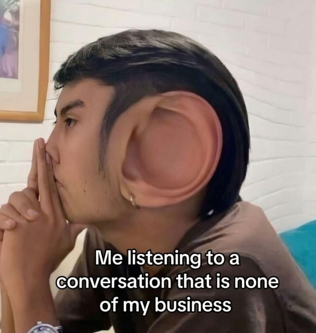 This is a humorous edited photograph depicting a young man in side profile. His right ear is digitally modified to be extremely exaggeratedly large, creating a comical visual gag. The man has a focused, intent expression, with his hands clasped together held up near his mouth as if he is concentrating intently on listening. The text overlaid at the bottom of the image reads 'Me listening to a conversation that is none of my business', which pairs with the giant ear visual to joke about the relatable, common behavior of nosily eavesdropping on other people's private conversations even when they have no relation to the listener.