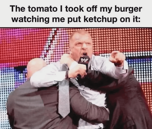 This meme features top text that reads: "The tomato I took off my burger watching me put ketchup on it:", paired with a photo of WWE personality Triple H being physically restrained by two security guards while he shouts angrily into a WWE branded microphone and points forward aggressively. The joke relies on personification: the removed fresh tomato is framed as being disproportionately enraged that the eater is choosing to use processed tomato-based ketchup instead of eating the fresh tomato they discarded, implying the tomato feels disrespected and made redundant.