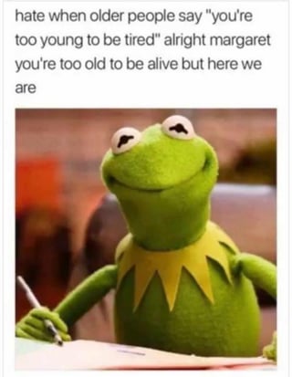 This relatable meme combines sarcastic text with a popular Kermit the Frog template to push back against dismissive generational remarks. The top text reads: *"hate when older people say 'you're too young to be tired' alright margaret you're too old to be alive but here we are"*, expressing frustration with older adults invalidating young people's fatigue through dark, sarcastic humor. Below the text, Kermit the Frog is shown sitting at a desk, holding a pen over a sheet of paper with a smug, amused expression, as if drafting or presenting this clapback. The meme resonates with audiences who have experienced similar dismissive comments, using a well-known character to amplify the relatable frustration.
