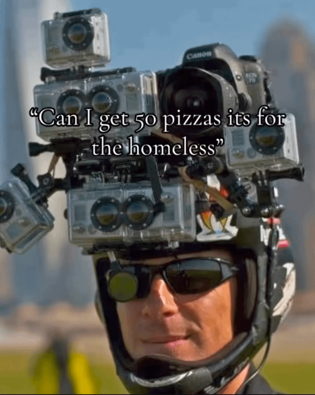 An image depicting a person wearing a helmet adorned with multiple mounted cameras (including a visible Canon camera). The individual is wearing sunglasses and has a neutral to slightly smirking expression. Overlaid text in the center reads: 'Can I get 50 pizzas its for the homeless'. The background is blurred, suggesting an outdoor setting with indistinct distant structures. The meme humorously implies skepticism about the legitimacy of a large charitable request by pairing the suspiciously excessive camera setup (evoking surveillance or scrutiny) with the request for 50 pizzas under the guise of helping the homeless.