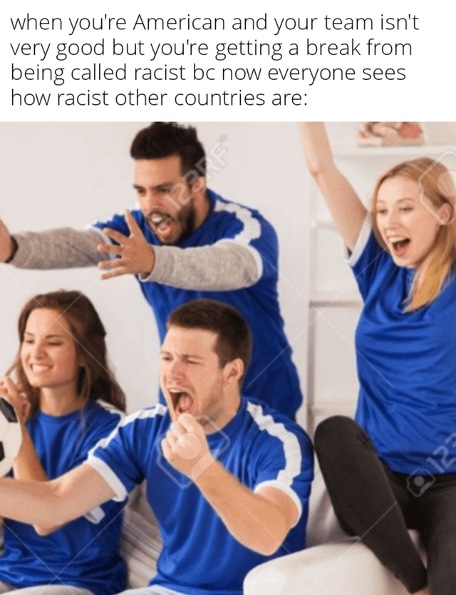 The meme is split into two parts: first, a line of text at the top that reads 'when you're American and your team isn't very good but you're getting a break from being called racist bc now everyone sees how racist other countries are:', followed by a stock photo of 4 young adult fans (2 men, 2 women) in matching blue sports jerseys cheering extremely enthusiastically while watching a sports event, with one woman holding a soccer ball. The joke is sarcastic commentary on discourse during major international soccer tournaments, where publicized instances of racism from fans of other participating nations temporarily shift widespread criticism away from American racial issues, even if the US national soccer team is not performing well.