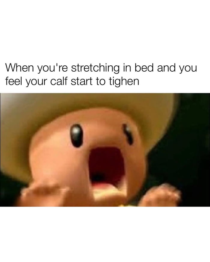 A meme consisting of a top text overlay and an image of an animated character. The text reads: 'When you're stretching in bed and you feel your calf start to tighten'. Below the text is a close-up of a small, round, orange animated character with large black eyes, a wide-open mouth (suggesting a scream or alarm), and raised hands. The character wears a large, floppy hat, and the background is dark, emphasizing the character's shocked expression. The meme humorously captures the universal experience of sudden discomfort when stretching, using the character's exaggerated reaction to convey panic.