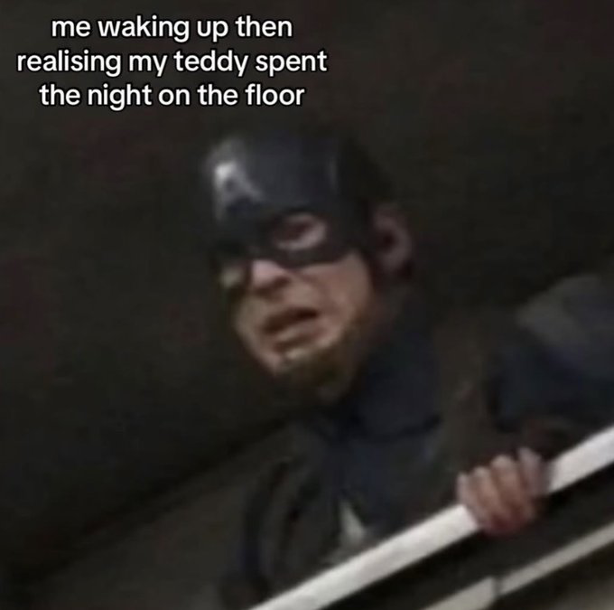 This is a relatable humor reaction meme that uses a blurry screencap of Captain America from the Marvel Cinematic Universe, who appears distressed and is gripping a railing while looking horrified. White overlaid text at the top of the image reads 'me waking up then realising my teddy spent the night on the floor'. The meme comically compares the intense, panicked reaction of Captain America in the original dramatic action scene to the relatable, overly dramatic small distress people who are attached to their stuffed animals feel when they wake up and find their teddy bear fell onto the floor overnight. The blurriness of the image also adds to the disoriented, half-asleep vibe of just waking up.