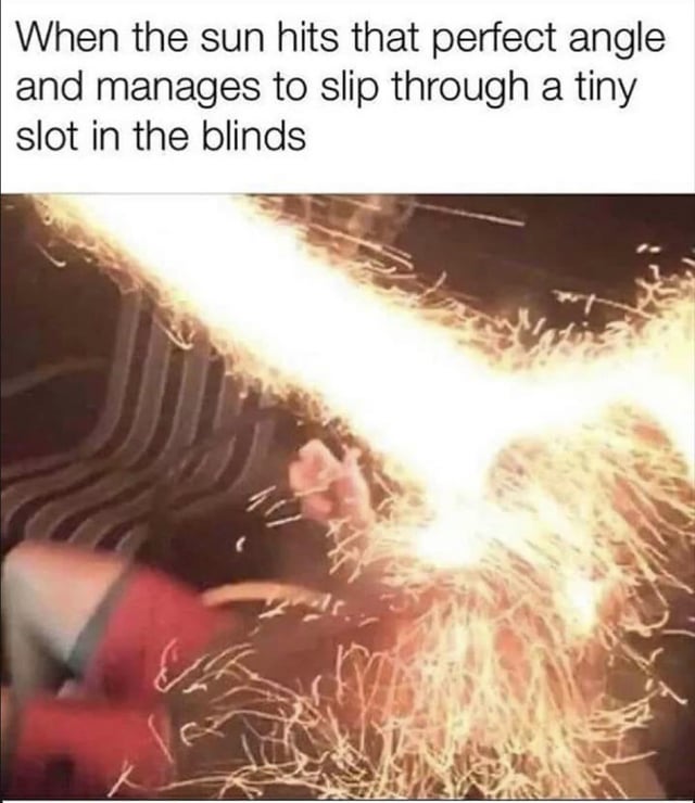 A meme featuring a top text caption and a lower image. The top text reads: 'When the sun hits that perfect angle and manages to slip through a tiny slot in the blinds'. The lower image shows a person lying down, with bright, intense light beams resembling sunlight streaming through blinds, creating a dramatic effect. The humor stems from the relatable scenario of sunlight unexpectedly interrupting a comfortable position, exaggerated by the intense visual of the light beams.