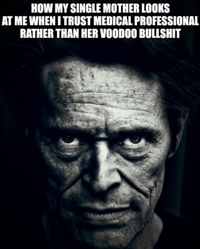 A black-and-white meme featuring a close-up of a person's face with an intensely stern, furrowed expression, conveying anger or disapproval. The text at the top reads: 'HOW MY SINGLE MOTHER LOOKS AT ME WHEN I TRUST MEDICAL PROFESSIONAL RATHER THAN HER VOODOO BULLSHIT'. The humor stems from the exaggerated, menacing reaction contrasted with the relatable family scenario of differing beliefs in conventional medicine versus traditional/folk remedies (referred to colloquially as 'voodoo bullshit').