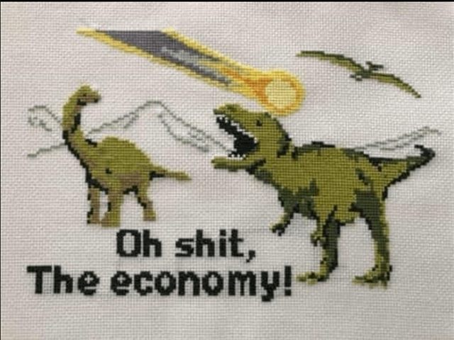 A cross-stitch artwork depicting two dinosaurs reacting to an incoming meteor. On the left, a green long-necked dinosaur (likely a Brachiosaurus) stands facing a green T-Rex on the right. The T-Rex has its mouth open, appearing to shout, while the Brachiosaurus looks on. Above them, a meteor with a yellow trail descends from the sky, evoking the Cretaceous-Paleogene extinction event. Below the dinosaurs, bold black text reads 'Oh shit, The economy!', blending prehistoric disaster imagery with commentary on modern economic concerns like inflation. The cross-stitch texture gives the image a handmade, nostalgic feel.