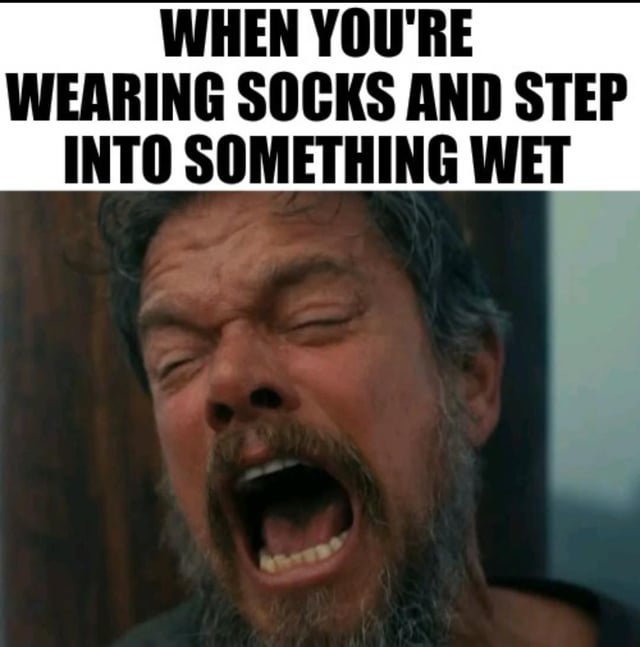 This is a relatable humorous meme. Bold all-caps black text at the top reads "WHEN YOU'RE WEARING SOCKS AND STEP INTO SOMETHING WET", positioned above a close-up shot of actor Matt Damon screaming with his eyes tightly shut and his face contorted in clear distress and disgust. The pairing perfectly illustrates the universal intensely negative visceral reaction most people have to the common unpleasant experience of accidentally getting their socks wet.