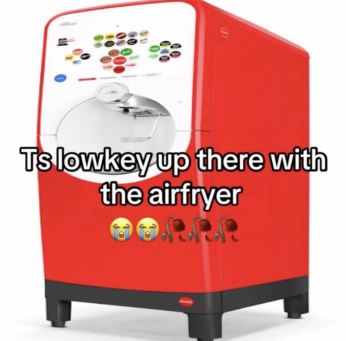 The image displays a red and white Coca-Cola Freestyle self-serve soda fountain, a machine that allows users to mix custom combinations of hundreds of different soft drink flavors. Overlaid on the lower half of the image is meme text that reads 'Ts lowkey up there with the airfryer' (a colloquial spelling of 'It's lowkey up there with the air fryer'), followed by two crying laughing face emojis and three wilted rose emojis. The meme expresses the opinion that the Coca-Cola Freestyle machine is an extremely desirable, impressive appliance that deserves the same level of praise and popularity as air fryers, which are widely regarded as one of the best modern household gadgets.