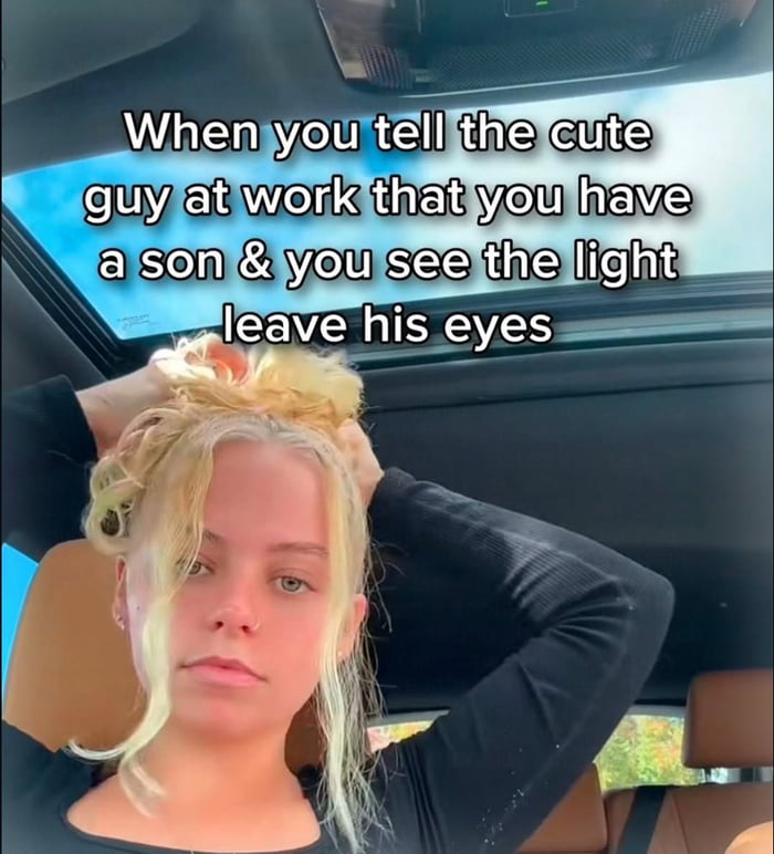 This meme features a real woman sitting inside a car, looking visibly dejected and tired with her hands holding up her messy blonde hair. The overlaid text reads: *When you tell the cute guy at work that you have a son & you see the light leave his eyes*. It humorously captures the relatable, disappointing moment when a romantic interest at work loses their enthusiasm upon learning the poster is a parent, using the woman's defeated expression to perfectly mirror the letdown described in the caption.