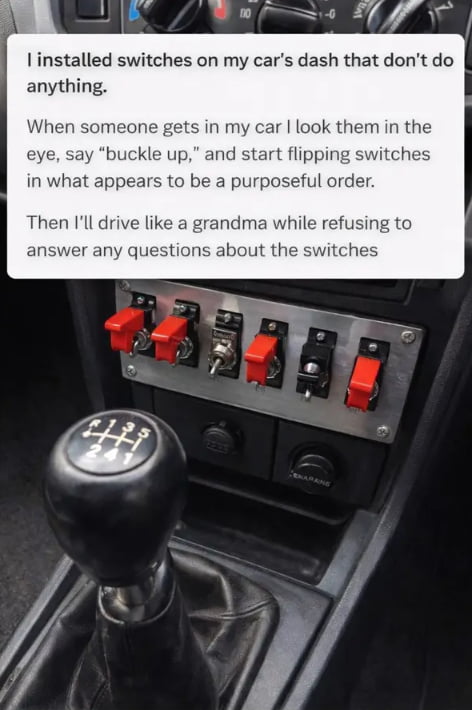 The image shows the interior of a manual transmission car, with a manual gear shifter in the foreground and a custom metal panel of toggle switches mounted on the lower dashboard. Overlaid text on the top of the image describes a lighthearted prank: the car owner installed non-functional switches on their dash. When passengers get in, the owner makes eye contact, tells them to buckle up, flips the useless switches in a seemingly intentional, purposeful order, then drives very slowly while refusing to answer any questions about the switches to deliberately confuse passengers and keep them guessing what the switches are for.