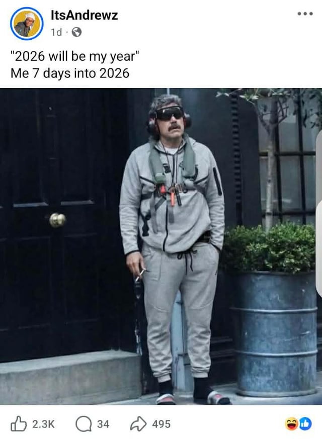 A Reddit meme posted by user ItsAndrewz, featuring two lines of text: '2026 will be my year' (expressing initial optimism for the new year) and 'Me 7 days into 2026' (depicting the reality after one week). Below the text is a photograph of a man standing in front of a black door and a large planter. He is wearing a gray tracksuit, sunglasses, and a harness with attached items, holding a cigarette in his hand, with a resigned or disillusioned expression. The meme humorously contrasts the common New Year's resolution optimism with the quick return to mundane or unfulfilled expectations.