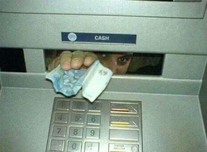 The image captures the front of an ATM machine, focusing on the cash dispensing slot marked with a 'CASH' label above it, with the standard numeric transaction keypad visible below the slot. In an absurd, humorous twist, instead of cash being dispensed automatically by the machine, a person's hand holding crumpled paper currency, along with their eyes and upper face, peek out from behind the cash slot, as if they are hiding inside the ATM and manually handing the withdrawn money to the user. The joke plays on the common silly, childlike assumption that real people work inside ATMs to process customer transactions.