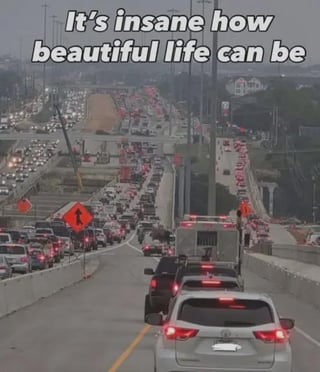 The image depicts a severe, gridlocked multi-lane highway traffic jam stretching far into the hazy distance, with construction warning signs visible along the roadside. Bold white text is overlaid at the top of the image, reading 'It's insane how beautiful life can be'. This creates a clear sarcastic ironic joke, as being stuck in heavy traffic is a widely recognized frustrating and unpleasant experience that directly contradicts the positive, appreciative sentiment of the overlaid text.