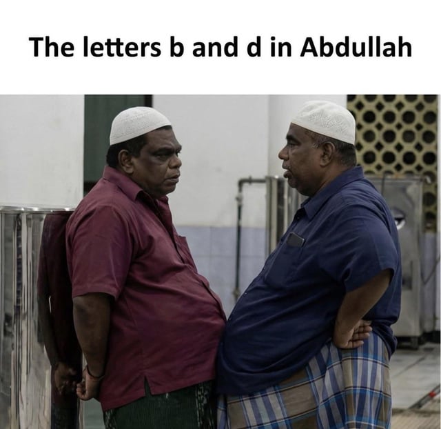 A meme featuring two men standing face-to-face in a setting that appears to be a mosque or religious facility, both wearing white caps, casual shirts, and traditional lungis. The top text reads 'The letters b and d in Abdullah,' creating a visual pun where the men's opposing positions mirror the mirror-image relationship between the letters 'b' and 'd' (which are visually similar but reversed), humorously referencing the potential confusion between these letters in spelling.