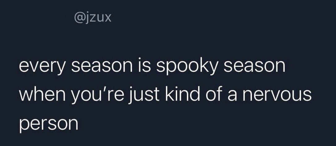 This is a minimal text-based meme featuring white sans-serif text on a solid dark navy background. The joke recontextualizes the popular term 'spooky season', which normally refers to the Halloween period in autumn, to apply year-round for people who are regularly nervous or anxious, as their baseline state of unease makes every time of year feel like a scary, spooky period. The creator's username @jzux is displayed at the top left of the image.