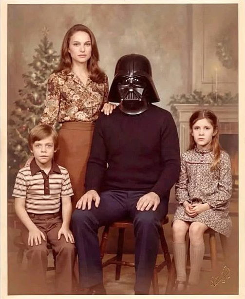 This is an edited vintage 1970s/80s style formal family Christmas portrait. The central seated father figure has his head replaced with Darth Vader's iconic black helmet from the Star Wars franchise. The family members are deliberately matched to the Skywalker family from Star Wars canon: the standing woman behind him resembles Natalie Portman, who played Padmé Amidala (Darth Vader's wife), while the young boy seated left is a stand-in for Luke Skywalker, and the young girl seated right is a stand-in for Leia Organa, the couple's twin children. All family members have neutral, serious expressions typical of old formal family photos, with a decorated Christmas tree and fireplace in the background. The humorous joke references the iconic 'I am your father' plot reveal from the Star Wars series, making the image perfectly suited for Father's Day content.