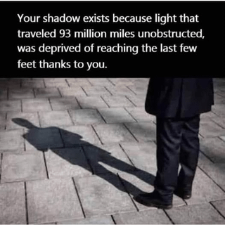 This meme features a real person (visible from the waist down, dressed in dark business attire) standing on a grey paved outdoor surface, with their long, stretched shadow extending forward in front of them. The top text provides a whimsical, scientific framing of the everyday phenomenon of shadows: it explains that a shadow exists because sunlight, which traveled 93 million miles unobstructed from the Sun, was prevented from reaching the final few feet of ground by the person's body. It's a playful, wholesome take on basic physics, framing the individual as a tiny but impactful obstacle to the vast journey of sunlight.