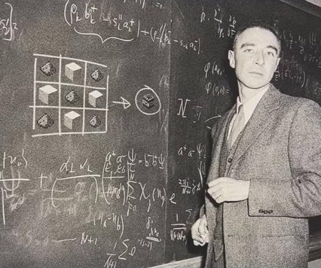 Black and white photograph of a middle-aged man in a suit standing next to a chalkboard filled with mathematical equations and diagrams. The chalkboard contains various handwritten formulas, including what appears to be algebraic expressions and geometric notations. On the left side of the chalkboard, there is a 3x3 grid with cube-like shapes, with an arrow pointing to a circled cube. The man stands to the right of the chalkboard, looking slightly to his left with a serious expression, his right hand partially raised near his chest.