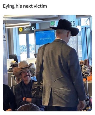 A humorous photograph set in an airport terminal near Gate 15, where a seated man wearing a cowboy hat appears to gaze playfully at another man in a suit and black hat walking past. The scene includes a visible 'Gate 15' sign and a 'LATE CLOSED' indicator. The title 'Eying his next victim' adds a comedic, lighthearted implication that the seated cowboy is mischievously targeting the passing individual.