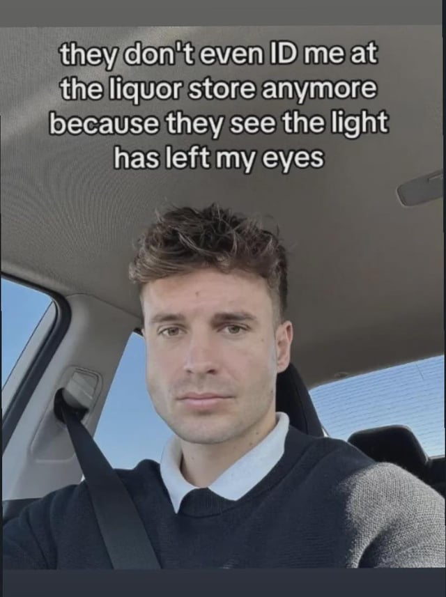 This meme features a selfie of a tired-looking man sitting in the driver's seat of a car, staring directly at the camera with a blank, empty expression. Overlaid text on the image reads 'they don't even ID me at the liquor store anymore because they see the light has left my eyes'. The joke plays on the common relatable idea that as people get older and go through the stress of adulthood, they lose the youthful 'spark' in their eyes, making them obviously old enough to buy alcohol that liquor stores don't need to check their ID anymore.
