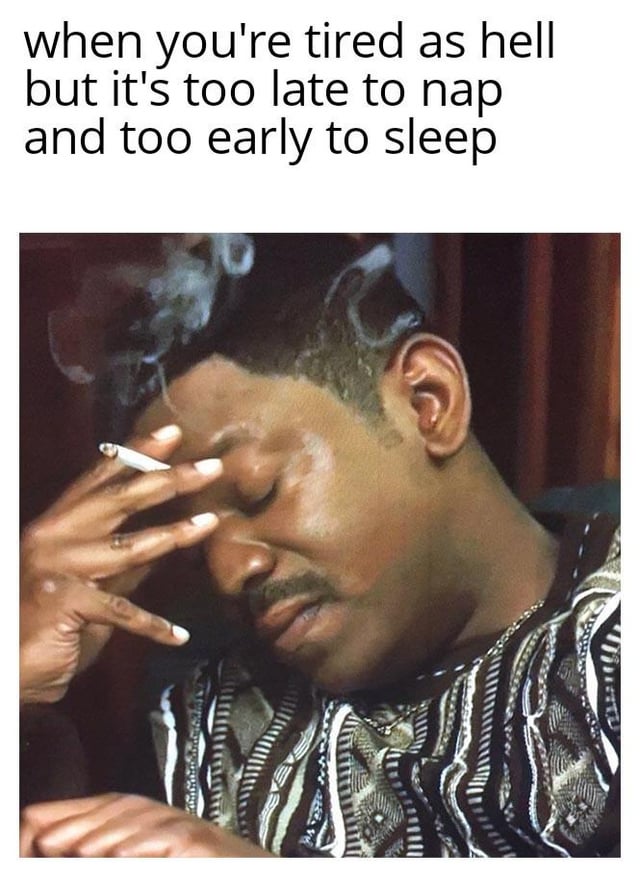 This is a single-panel relatable meme. The top section contains text describing the common late afternoon dilemma: being extremely tired, but it is too late in the day to take a nap without ruining nighttime sleep, while also being too early to go to bed for the night. Below the text is a viral reaction photo of a Black man holding a lit cigarette, pressing his hand to his forehead with his eyes closed, looking visibly exhausted, defeated, and frustrated, perfectly embodying the annoying, tired feeling described in the text. The meme refers to the common 5-7 PM window where this tiredness dilemma often occurs.