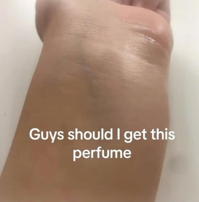 This is a crude, absurdist meme showing a close-up of the back of a person's hand, which has a clear, shiny, wet substance spread across its surface. White overlaid text on the image reads 'Guys should I get this perfume'. The humor derives from the suggestive, intentionally misleading framing: the wet substance is clearly not actual perfume, and is heavily implied to be a bodily fluid such as spit or semen, with the poster pretending to seriously ask for advice about purchasing it as a fragrance for comedic effect.