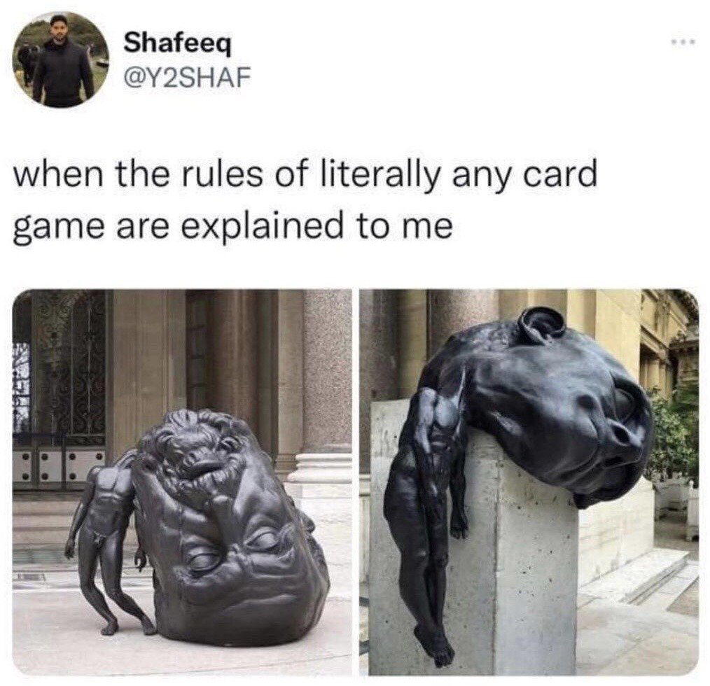 This is a screenshot of a tweet from X (formerly Twitter) user Shafeeq (@Y2SHAF). The tweet text reads 'when the rules of literally any card game are explained to me', paired with two images of surreal dark bronze public sculptures. The left image shows a small human-like sculpted figure collapsed and leaning against a giant, oversized, tired-looking human head sculpture resting on the ground in front of a stone building. The right image shows a similar small human sculpted figure completely limp and draped lifelessly over a giant oversized human head sculpture placed on a concrete pedestal. The two images comically visualize the relatable feeling of being totally overwhelmed, mentally exhausted, and checked out when trying to process complicated, confusing card game rules.