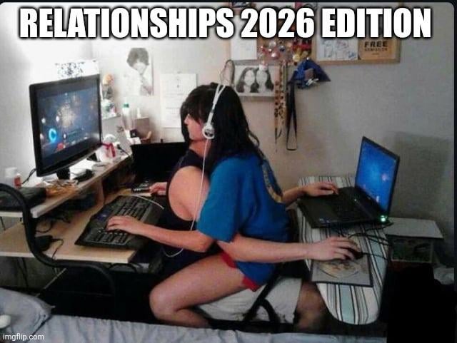 The meme displays a couple in a shared bedroom space with gaming setups, positioned in an awkward overlapping seated arrangement so both can play video games simultaneously. A woman wearing headphones sits on her male partner's lap facing left, playing a game on a desktop PC using a keyboard. The man sits behind her, reaching around her body to use a laptop and mouse placed on a table to his right, playing his own game. The bold text at the top reads 'RELATIONSHIPS 2026 EDITION', making a humorous joke about how modern romantic relationships for gaming couples prioritize accommodating each other's hobbies to spend time together, even if it means taking on physically uncomfortable positions.