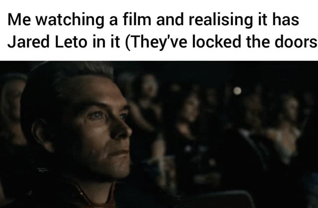 This is a single-panel reaction meme. The top section has black text on a white background reading "Me watching a film and realising it has Jared Leto in it (They've locked the doors". Below the text is a dark screenshot of the character Homelander from *The Boys* sitting in a crowded movie theater, with a resigned, dismayed, trapped expression. The joke relies on the common internet sentiment that Jared Leto's performances, especially his role as the titular character in the 2022 poorly received film *Morbius*, are unpleasant to watch, so realizing he is in the film you are already viewing in a theater with locked doors you cannot exit through is a relatable, humorous unpleasant experience tied to the viral "Morbin' time" meme trend.