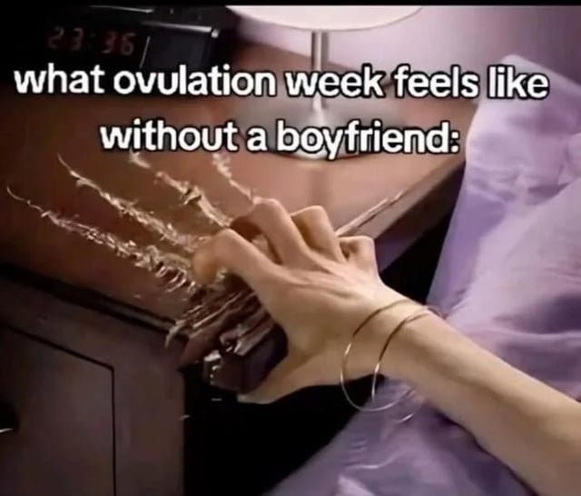 This is a reaction meme showing a close-up of a person's hand aggressively creating deep scratch marks into the surface of a wooden nightstand next to a bed with lavender bedding, with a digital clock reading 23:36 visible in the top left corner. The overlaid text reads 'what ovulation week feels like without a boyfriend:', using the extremely agitated, frustrated action of scratching furniture as an exaggerated visual metaphor for heightened sexual frustration experienced by single people during the ovulation phase of the menstrual cycle, which is commonly associated with increased libido.