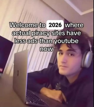 This meme features a photograph of a real young man wearing headphones sitting at a desk with an open laptop, overlaid with text that jokes that by 2026, unregulated piracy websites actually have fewer intrusive advertisements than the mainstream video platform YouTube. The satirical joke highlights the common user frustration that YouTube has become increasingly overloaded with ads, even multiple unskippable ads before short videos, to the point that piracy sites now offer a better ad experience than the official platform.