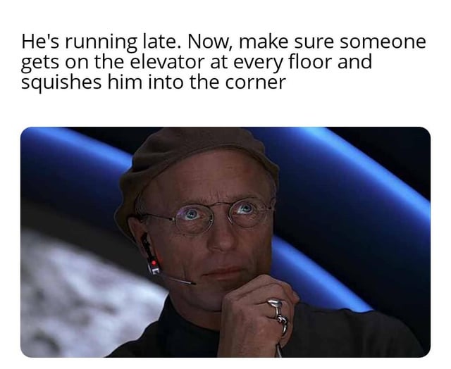 This is an image macro meme. The top text reads "He's running late. Now, make sure someone gets on the elevator at every floor and squishes him into the corner". Below the text is a still of the character Christof from *The Truman Show*, who is resting his chin on his hand, wearing a communications headset, and looking upward with a scheming, plotting expression. The joke leans into relatable petty, exaggerated annoyance at people running late, framing the petty desire to inconvenience them as an evil orchestrated plan, matching the character's canonical role as the all-controlling creator of Truman's fabricated world.
