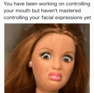 The meme features a close-up photograph of a doll with long brown hair, large wide eyes, and slightly parted lips, creating an exaggerated surprised or shocked facial expression. Positioned above the doll's face is a text overlay that reads: 'You have been working on controlling your mouth but haven't mastered controlling your facial expressions yet.' The humor is derived from the relatable scenario where an individual attempts to censor their words to hide their true thoughts or reactions but fails because their involuntary facial expressions betray their feelings. The doll's overtly expressive features amplify this contrast, making the meme both funny and relatable.