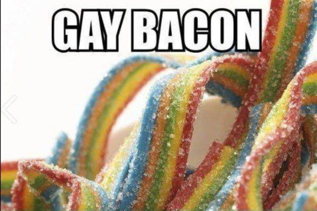 A meme featuring bold, uppercase white text 'GAY BACON' positioned at the top, with a close-up image of rainbow-striped (red, orange, yellow, green, blue) sugary candy strips resembling bacon. The candy appears glossy and coated in sugar, mimicking the appearance of cooked bacon but in vibrant rainbow colors. The humor stems from a pun: the rainbow colors reference the LGBTQ+ pride flag, playfully pairing it with 'bacon' (a popular savory food item) to create a lighthearted, whimsical visual joke.