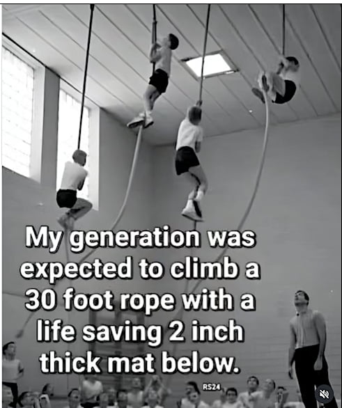 A black and white photograph depicting a gymnasium scene where several children climb 30-foot ropes, with a supervising adult standing below and other children observing. Overlaid text humorously states: 'My generation was expected to climb a 30 foot rope with a life saving 2 inch thick mat below.' The image contrasts past generational experiences with perceived safety standards, using sarcasm to highlight the minimal protective measures (a thin mat) for a risky activity.