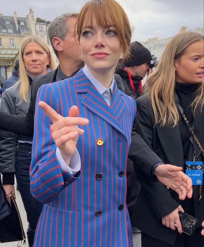 The image depicts a woman in a blue blazer with red vertical stripes standing among a crowd in an outdoor urban setting, likely Paris, given the background architecture. She is pointing upwards with her right hand and has a curious, inquisitive expression. The humor stems from the original 9Gag title, which jokes that her demeanor suggests she is about to ask a historian a suggestive question about King Arthur (playing on the double meaning of 'came' as 'arrived' versus a sexual innuendo).