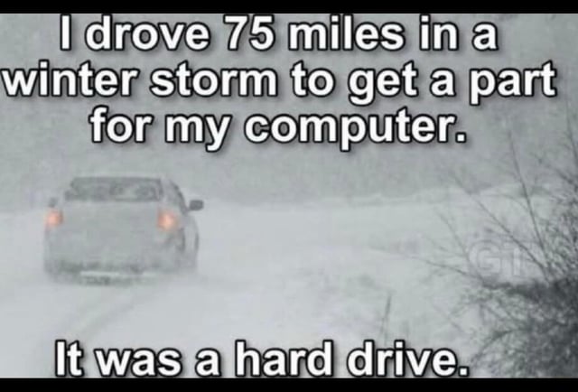 A meme consisting of a photograph of a car driving through a heavy winter storm with snow-covered roads and reduced visibility. Overlaid text reads: 'I drove 75 miles in a winter storm to get a part for my computer. It was a hard drive.' The humor relies on a pun: 'hard drive' refers both to the computer storage component and the difficult (hard) driving experience through the storm.