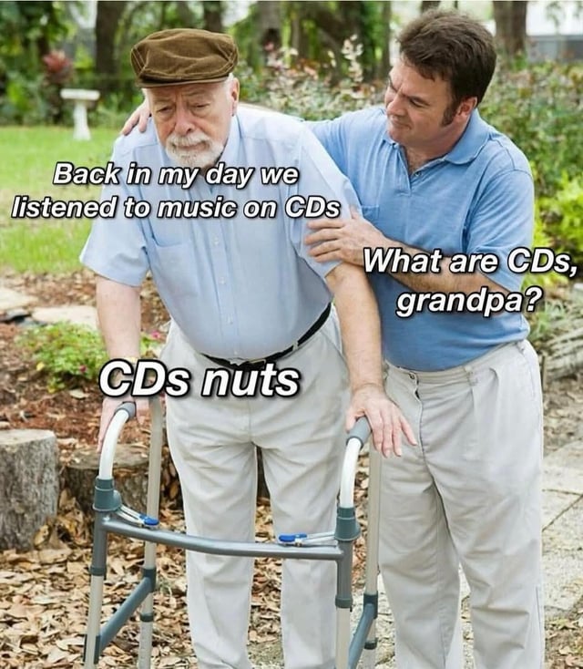This is a classic "got 'em" prank pun meme featuring an elderly grandfather using a mobility walking frame, being assisted by his adult grandson while walking outdoors in a garden. The meme sets up a natural generational conversation: the grandfather reminisces saying "Back in my day we listened to music on CDs", the grandson asks confusedly "What are CDs, grandpa?", and the grandfather delivers the punchline "CDs nuts". This is a pun on the viral internet prank joke "deez nuts", using "CDs" to sound like "see deez", pulling the classic prank on his grandson for comedic effect.