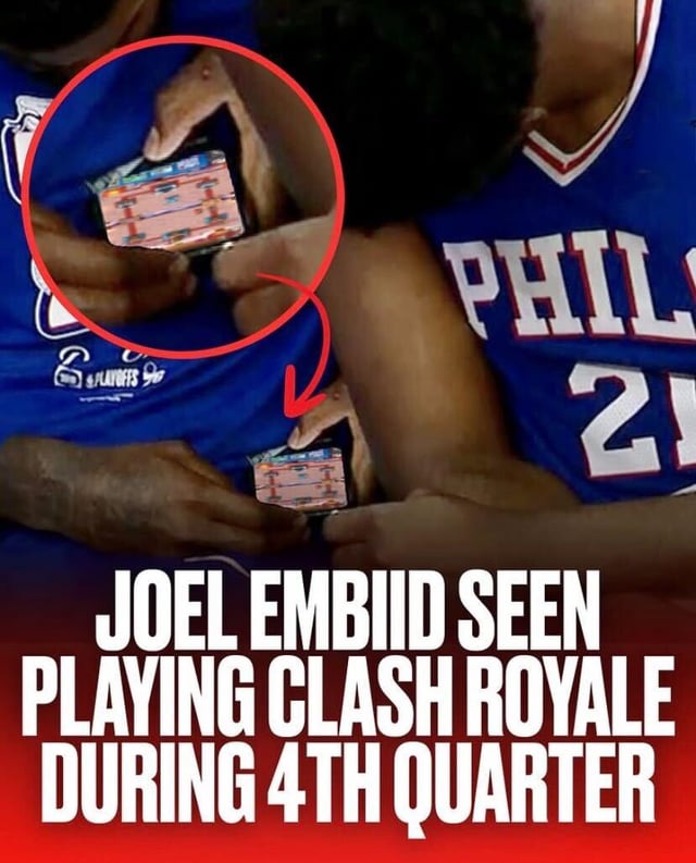 The image depicts two basketball players wearing blue Philadelphia 76ers jerseys, with the player in the foreground (Joel Embiid, identifiable by jersey number 21) holding a smartphone. A red circular highlight with an arrow points to the phone screen, which displays the game Clash Royale. Below the image, large white text reads 'JOEL EMBIID SEEN PLAYING CLASH ROYALE DURING 4TH QUARTER', creating a humorous scenario of the NBA player being distracted by mobile gaming during a game.