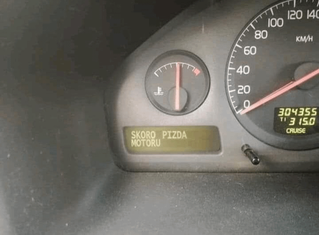 A close-up photograph of a car's dashboard focusing on the instrument cluster. The speedometer shows approximately 10 km/h, with a digital odometer reading '304355' and '7.3 15.0' below it, accompanied by a 'CRUISE' indicator. A small digital display below the speedometer shows the text 'SKORO PIZDA MOTORU' in yellow. 'Pizda' is Polish slang for a vulgar term, making the phrase nonsensical and humorous, likely due to a software glitch or intentional editing for comedic effect.