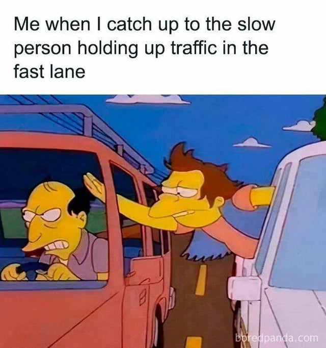 A meme consisting of a top text overlay and a screenshot from the animated TV show 'The Simpsons'. The top text reads: 'Me when I catch up to the slow person holding up traffic in the fast lane'. Below the text, two animated drivers are depicted in cars on a road: the left driver (in a red car) has an angry expression with furrowed brows and gritted teeth, gripping the steering wheel tightly; the right driver (in a white car) leans out of the window, extending an aggressive arm gesture towards the left driver, with a determined, intense look. A watermark 'boredpanda.com' is visible at the bottom right corner. The meme humorously captures the frustration of encountering slow-moving vehicles blocking the fast lane, using recognizable animation from 'The Simpsons' to enhance relatability.