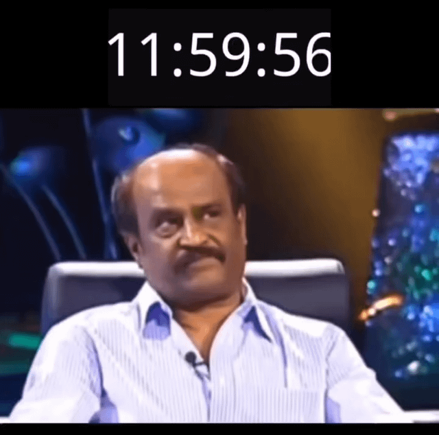 A meme image featuring a man sitting in a chair with a serious, slightly side-eyed expression. At the top of the image, there is a timestamp reading '11:59:56', suggesting the moments just before midnight on New Year's Eve. The background consists of blurred, colorful abstract elements, likely from a studio or stage setting, creating an anticipatory atmosphere. The original title 'Happy new year everyone' indicates the meme relates to New Year's celebrations, using the man's expression to convey the tension or expectation of the countdown.