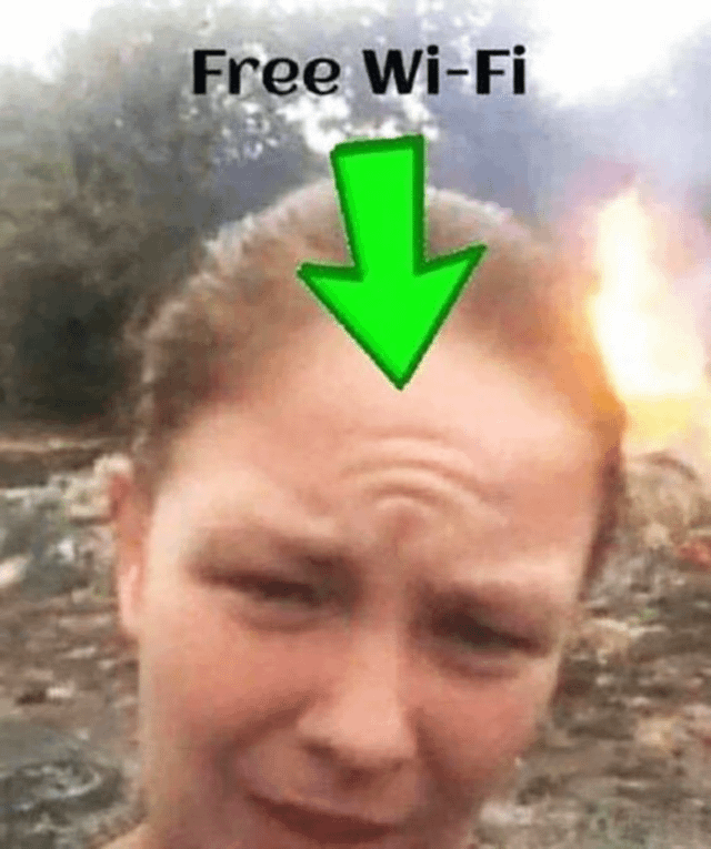 A meme image featuring a person with a distressed and worried facial expression. At the top of the image, the text 'Free Wi-Fi' is displayed in bold black letters. A large green arrow is superimposed, pointing directly to the person's head. In the background, there is a visible fire, creating a chaotic or urgent scene. The combination of the text, arrow, and the person's anxious look suggests a humorous or sarcastic take on prioritizing free Wi-Fi access even in distressing or dangerous situations.