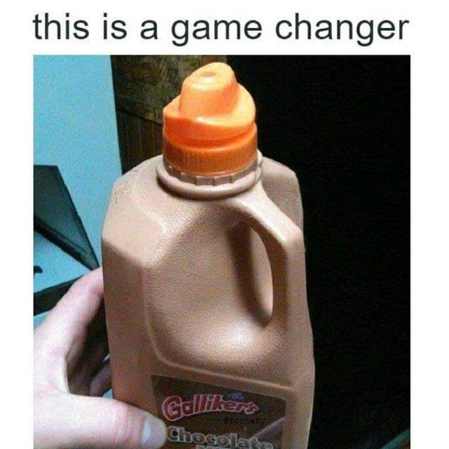 This image displays a clever DIY life hack: a large Galliker's chocolate milk jug has had its original big cap replaced with an orange twist flip cap from a liquid coffee creamer bottle, turning the wide, messy spout of the milk jug into a controlled, spill-resistant pour opening. Text at the top of the image reads 'this is a game changer', framing this simple modification as a surprisingly effective solution to the common annoyance of spilling when pouring from large beverage jugs.