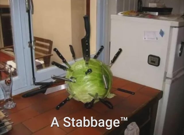 The meme displays a whole green head of cabbage set on a red-tiled kitchen counter, with numerous kitchen knives of varying sizes plunged into it from every direction, giving the cabbage the appearance of a pincushion or a voodoo doll. The text overlaid at the bottom reads 'A Stabbage™', a comedic pun that blends the words 'stab' (referring to the knives stuck in the vegetable) and 'cabbage' (the vegetable itself). The background features a small compact white refrigerator, a glass door leading to an adjacent room with a wooden slatted chair, and miscellaneous small kitchen items like a tall empty glass near the door.